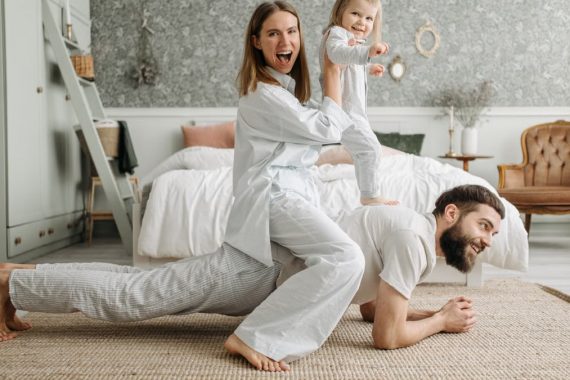 A cheerful family enjoys bonding and playing together on a cozy morning in a stylish bedroom.