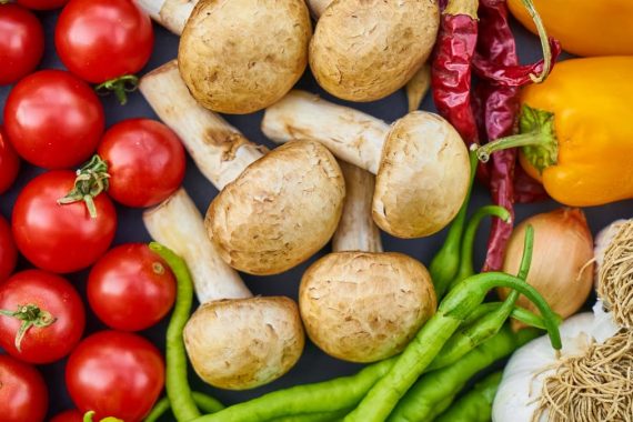 A vibrant assortment of fresh vegetables and mushrooms arranged in a flat lay.